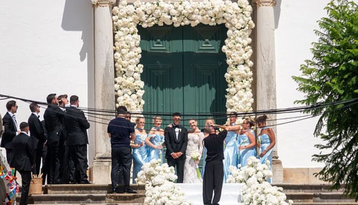 The groom and bride being photographed alongside bridesmaids dressed in blue